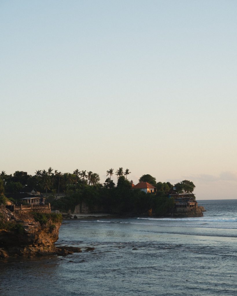 Soft dusk light over a cliffside headland and palm trees, a popular sunset spot on Nusa Lembongan