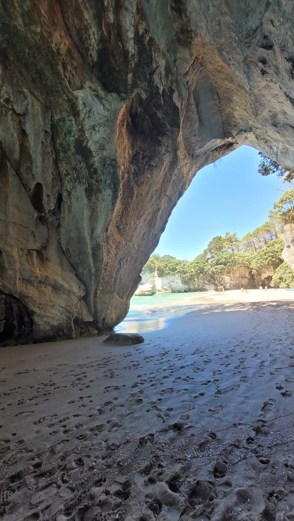 View looking out through the rock archway of Cathedral Cove onto the sandy beach and sea beyond