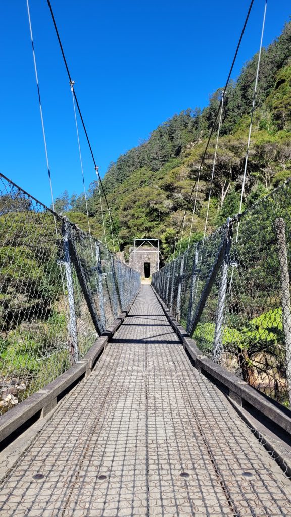 A suspension swing bridge crossing Karangahake Gorge, leading toward an old railway tunnel