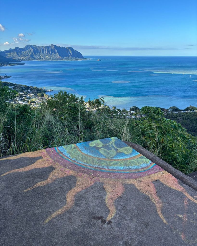 Painted sun mural on a pillbox rooftop overlooking Kaneohe Bay and mountain ridges in the distance