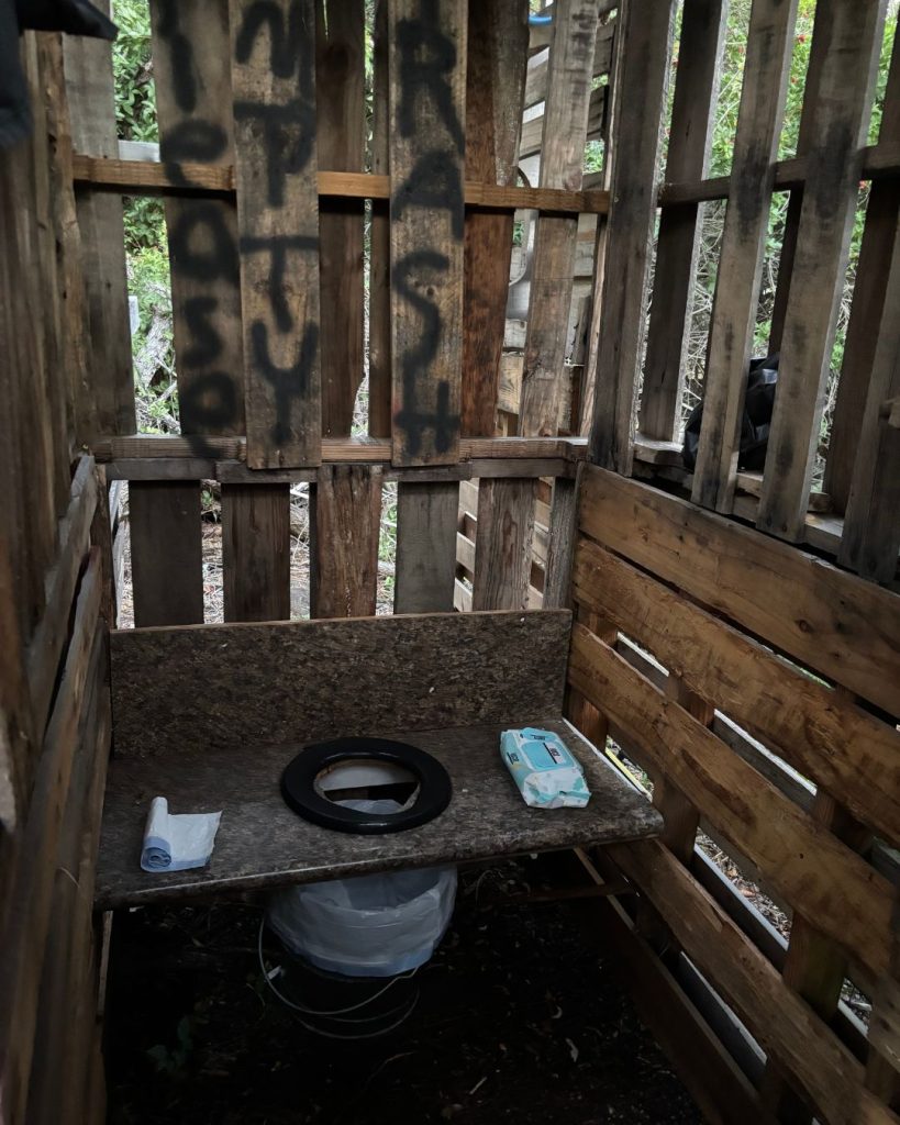 A rough wooden outhouse with a composting toilet at a remote campsite