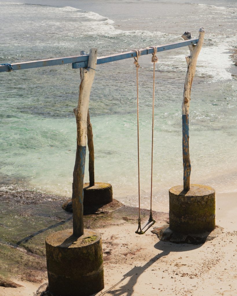 Wooden beach swing over clear turquoise water on Nusa Lembongan