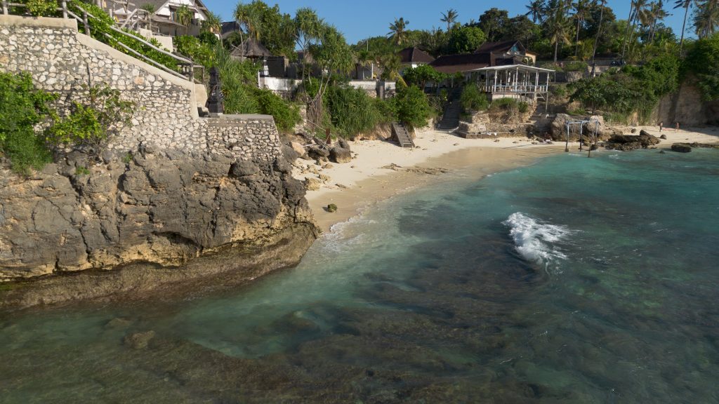 Aerial view of a rocky cove and beachfront villas on Nusa Lembongan's coast