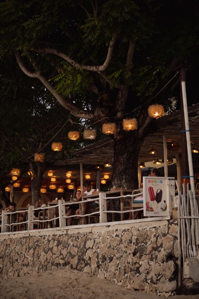 Beachside restaurant lit with lanterns under a tree at night on Nusa Lembongan