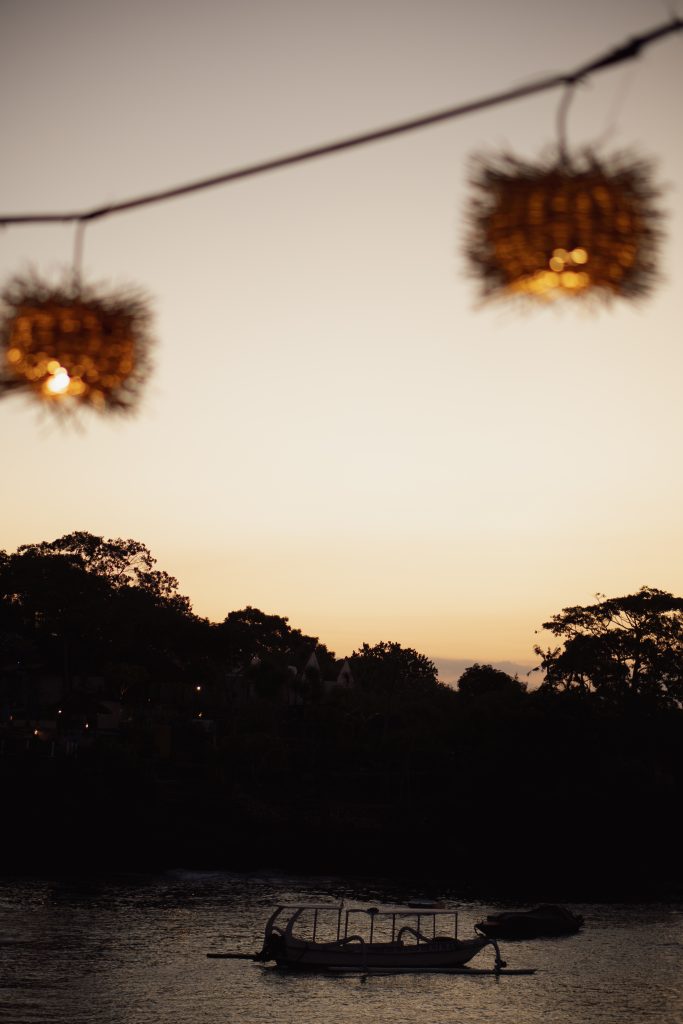 Silhouette of a traditional boat at sunset with lanterns on Nusa Lembongan