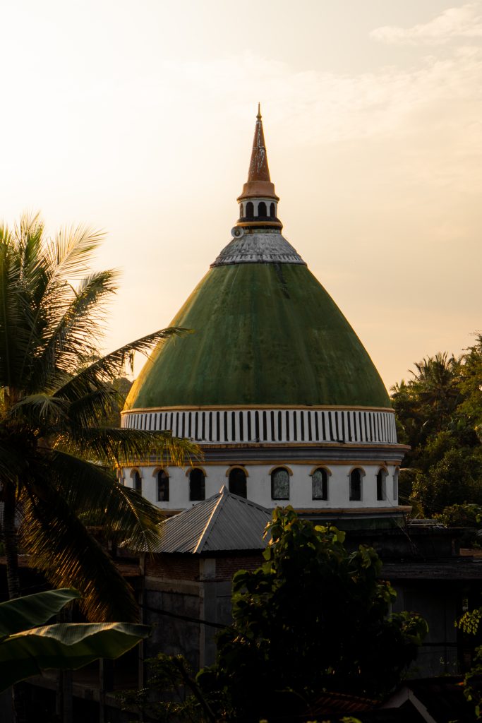 Green-domed village mosque framed by palm trees in Lombok at the end of the day