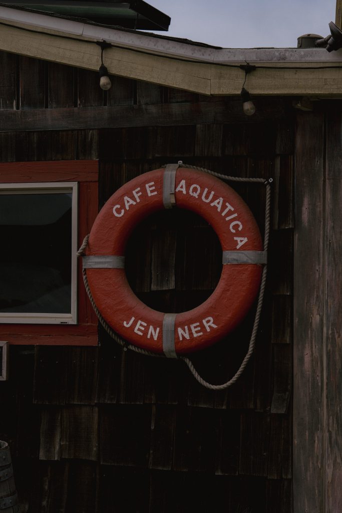 A life ring marked Cafe Aquatica Jenner hanging on the wooden wall of the cafe