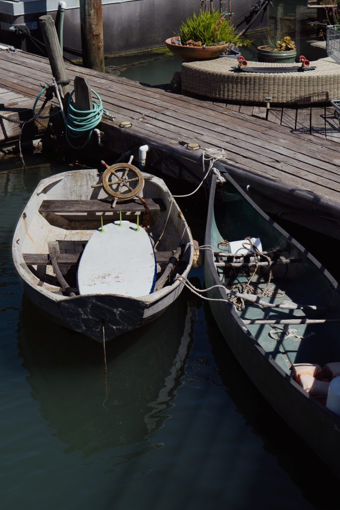 Small wooden boats tied up beside a floating home deck in Sausalito