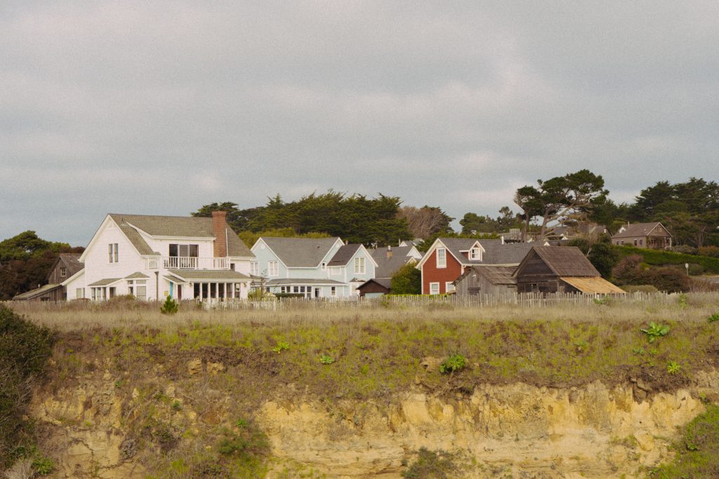 White clapboard houses perched on the cliff edge above the ocean in Mendocino