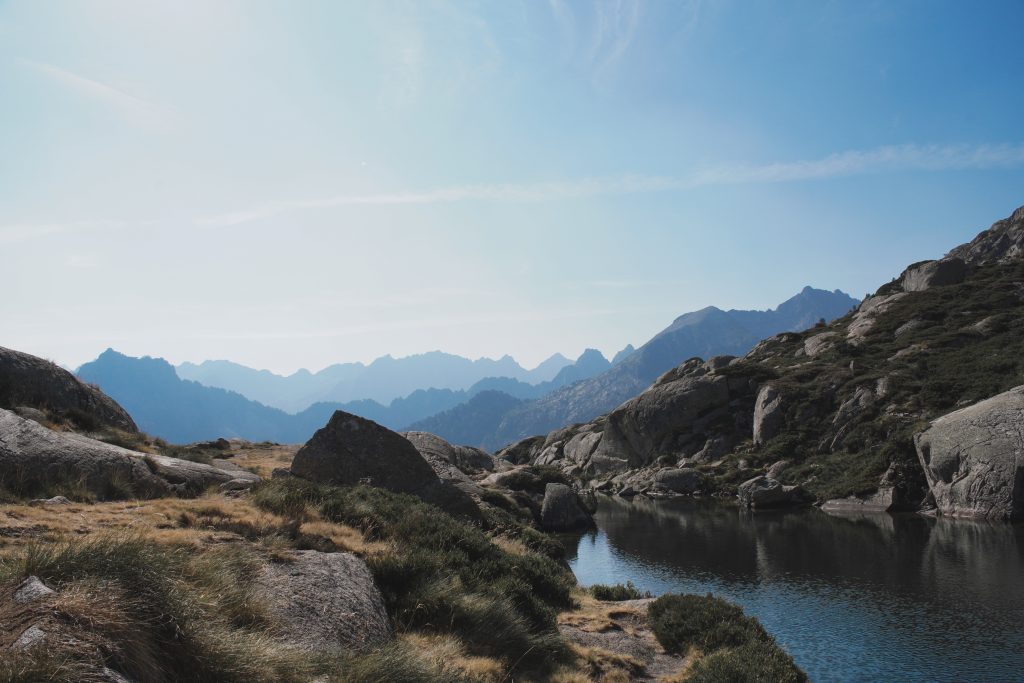 Glacial lake surrounded by rocks and Pyrenean peaks, in morning light, along the trail to the Wallon-Marcadau refuge.