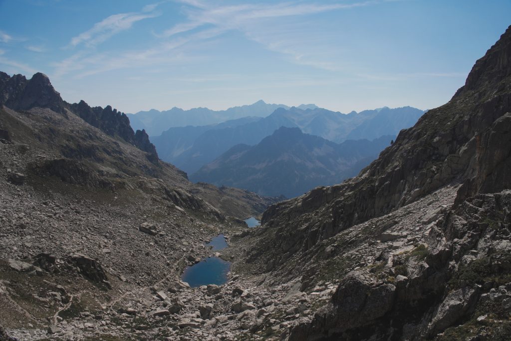 Panoramic view from above of several high-altitude lakes nestled among the rocks, with Pyrenean peaks in the background.