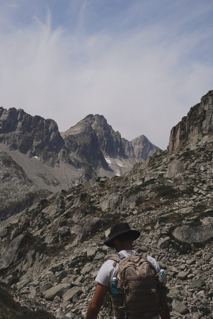 Pic rocheux escarpé avec un chapeau posé sur les rochers au premier plan, lors d'une pause pique-nique en montagne.