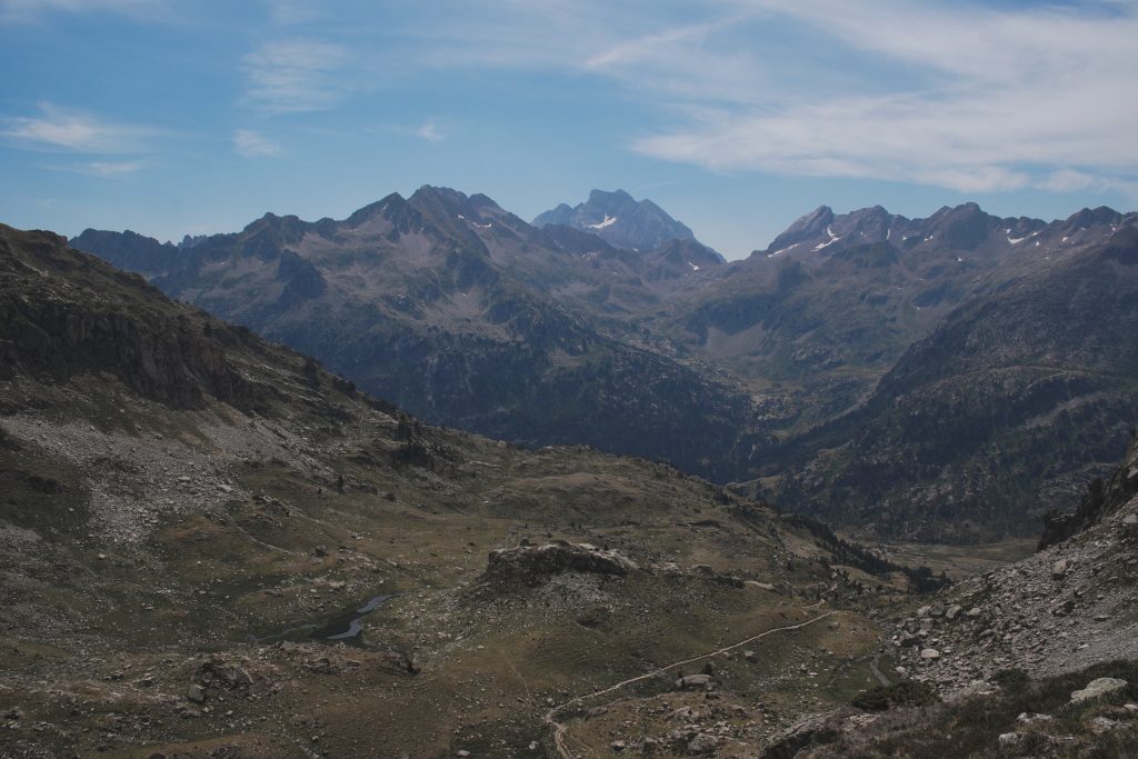 Panoramic view of the Marcadau mountain range under a blue sky, illustrating the vastness of the Pyrenean landscape.