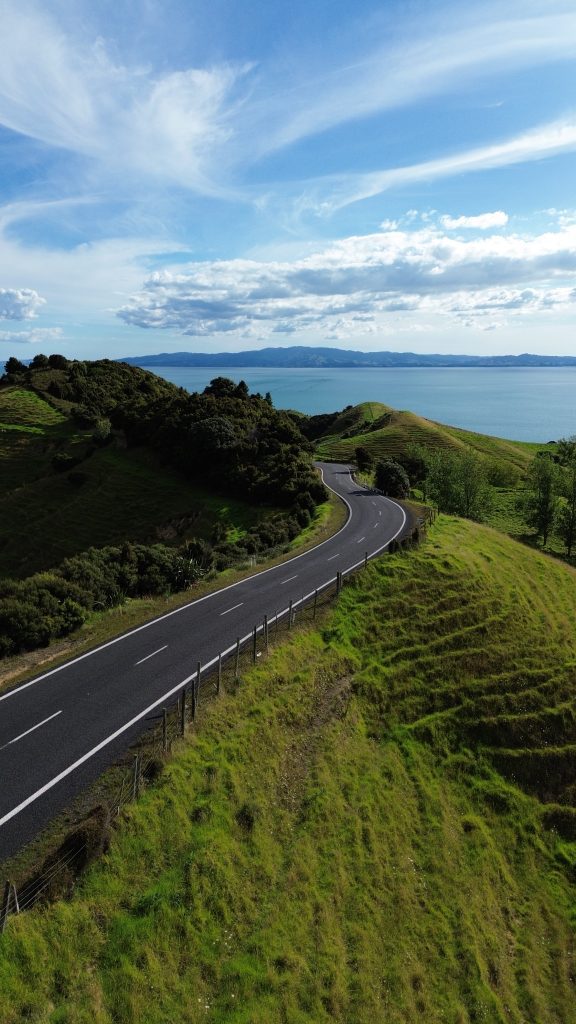 Wide sky view over green hills and the sea along the Coromandel Peninsula coastline