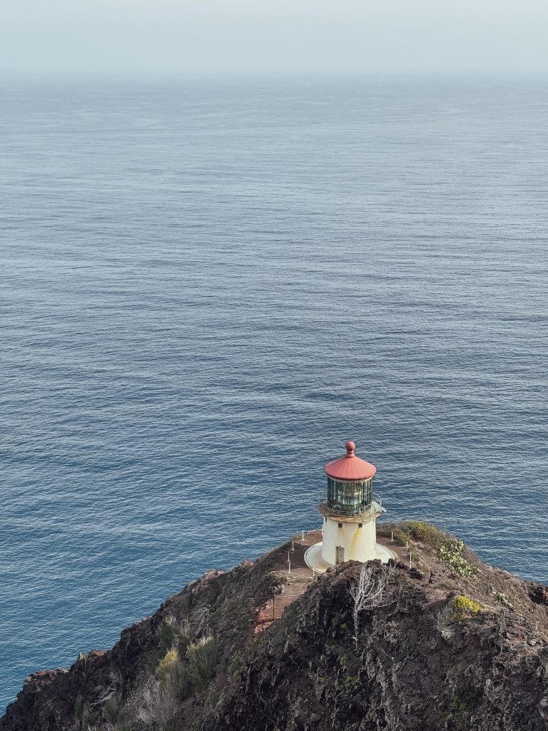 Makapuu Point Lighthouse perched on a rocky cliff above the ocean, viewed from above