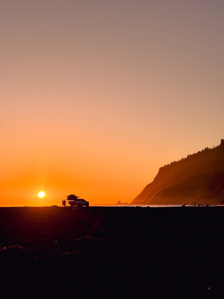 Sunset over the Pacific from Usal Beach campground on the Lost Coast, with a van parked on the sand
