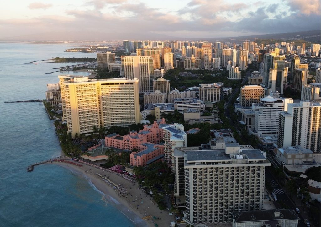 Aerial view of Waikiki's beachfront hotels and skyline along the coast at sunset