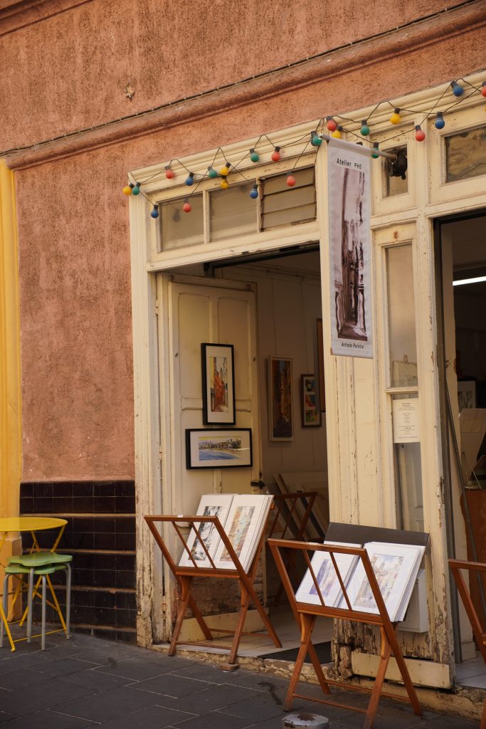 Art gallery in Vieux Nice with framed prints displayed on easels on the pavement under a string of lights
