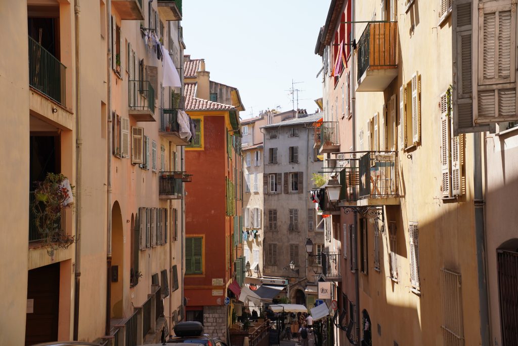 Narrow street in the old town of Nice lined with ochre and dusty pink buildings, one of the classic things to do in Provence